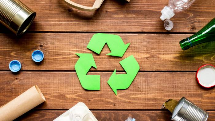 Eco concept with recycling symbol and garbage on wooden table background top view