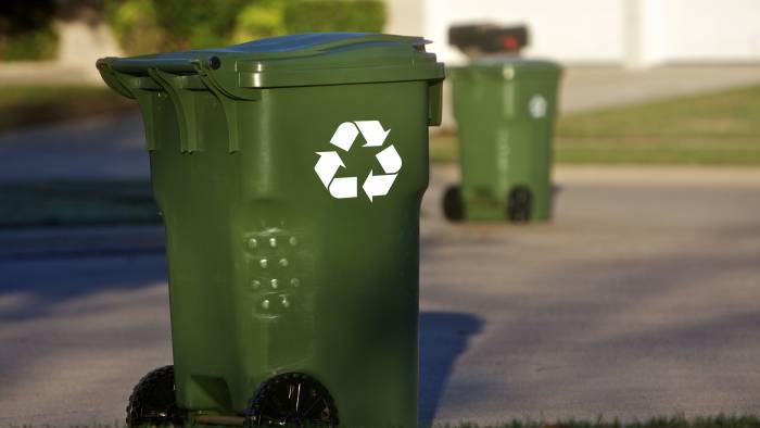 Green recycle bins align a neighborhood street